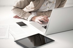 Modern office setup with laptop, smartphone, and tablet on a white desk, promoting productivity.